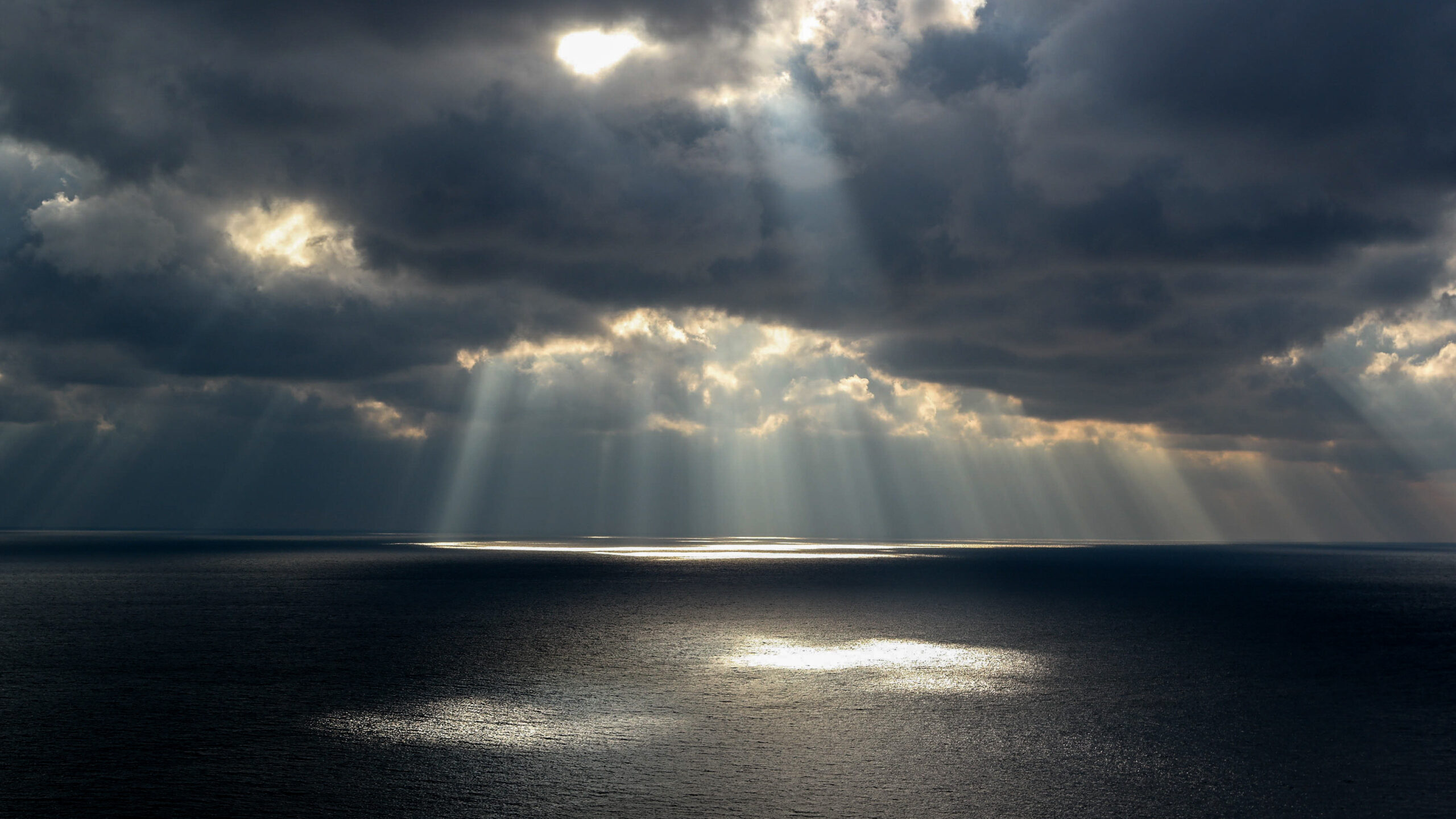 sun and clouds over a calm expanse of open ocean